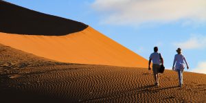 man and woman walking on desert